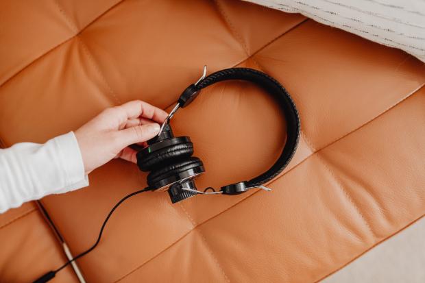 A person holding their headphones. Credit: Canva